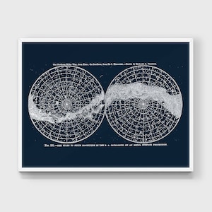 May include: A framed print showing a vintage map of the Milky Way galaxy. The artwork presents two circular projections of the night sky, with detailed star patterns and text. The background is a dark navy blue, and the print is in a white frame.