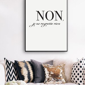 Puede incluir: Impresi&oacute;n enmarcada en blanco y negro con la frase francesa "NON, je ne regrette rien" que se traduce como "No, no me arrepiento de nada". La impresi&oacute;n est&aacute; colgada en una pared blanca sobre un sof&aacute; blanco con almohadas decorativas.