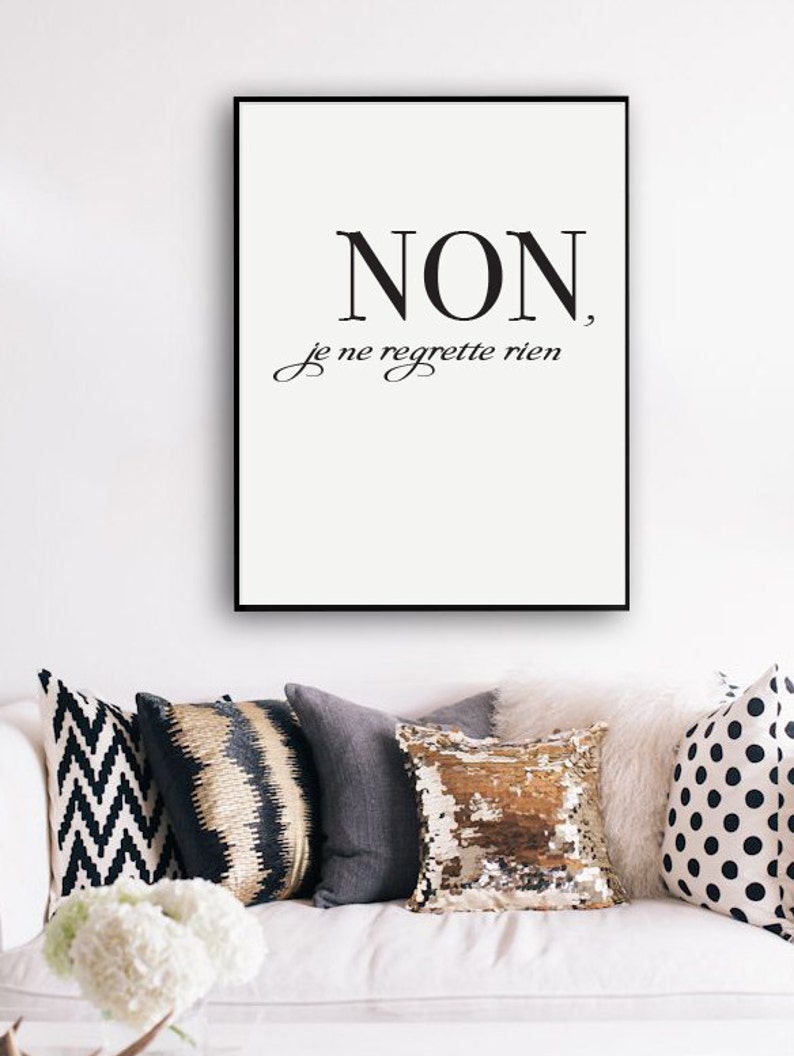 Puede incluir: Impresi&oacute;n enmarcada en blanco y negro con la frase francesa "NON, je ne regrette rien" que se traduce como "No, no me arrepiento de nada". La impresi&oacute;n est&aacute; colgada en una pared blanca sobre un sof&aacute; blanco con almohadas decorativas.