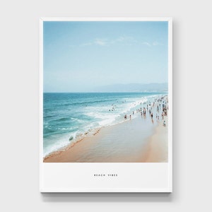 May include: A photograph of a beach scene with a sandy shore, blue ocean water, and a group of people in the distance. The text "Beach Vibes" is printed at the bottom of the image.