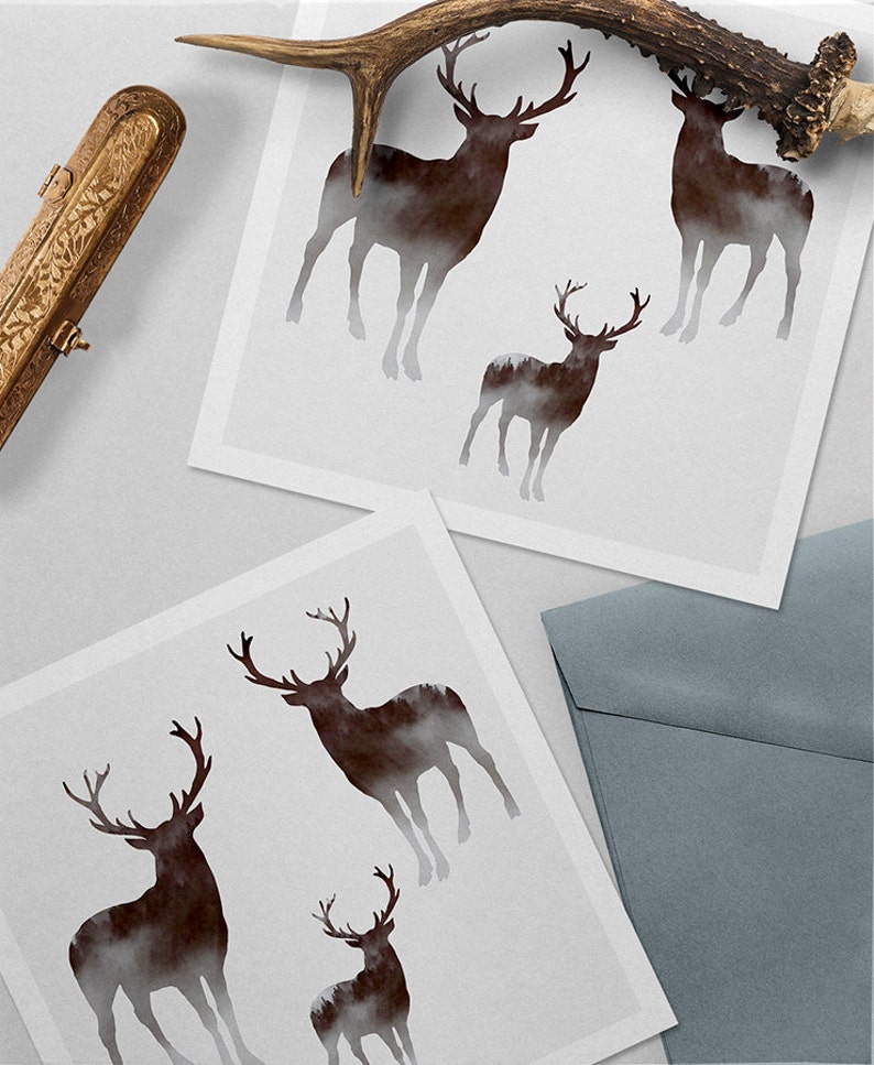 Puede incluir: Cuatro im&aacute;genes de silueta de ciervos con un fondo de bosque brumoso impresas en tarjetas blancas. Las tarjetas est&aacute;n dispuestas sobre una superficie gris con una caja decorativa dorada y una cornamenta marr&oacute;n.