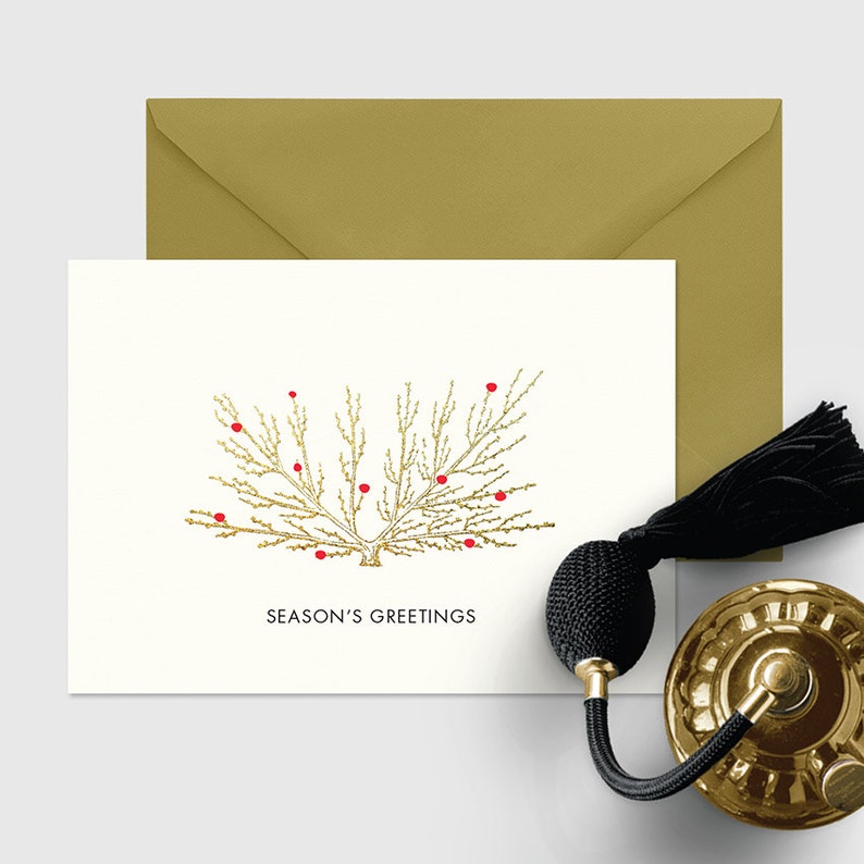 May include: A white card with a gold glitter tree with red berries and the text "Season's Greetings". The card is on a gold envelope.