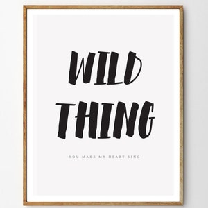 Op de afbeelding: Zwart-wit typografie print met de tekst "WILD THING YOU MAKE MY HEART SING" in een ingelijste poster.