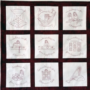 May include: A white fabric quilt square with red embroidered text and images. The text reads "Housework who has time?", "Sunday is for dreaming", "Monday is for shopping", "Tuesday is for piecing", "Wednesday is for appliqué", "Thursday is for assembly", "Friday is for quilting", "Saturday is for Show N. Tell". The images depict a spider web, a person in a hammock, two people shopping, a person sewing, a person appliquéing, a quilt block, a person quilting, and a quilt block.