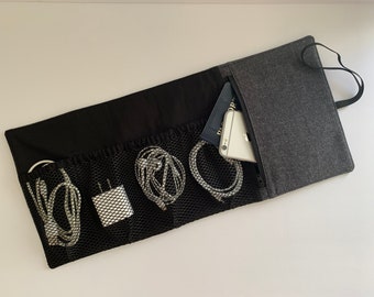 May include: A black and gray travel organizer with multiple mesh pockets for cords and a zippered pocket for a phone and passport.