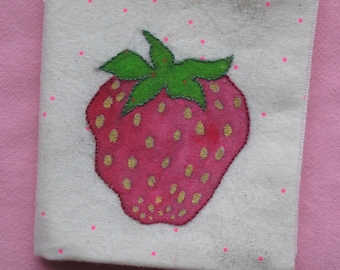 May include: A white fabric pouch with a pink and gold strawberry design. The strawberry has a green stem and leaves. The pouch has pink polka dots.