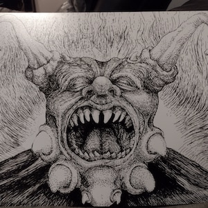 May include: A black and white pen and ink drawing of a grotesque, demonic creature with a large, open mouth and sharp teeth. The creature has horns and a large, bulbous nose.