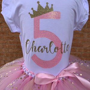 May include: A pink and gold tutu with gold polka dots and a pink satin bow. A white t-shirt with a pink number 5 and a gold crown, and the name Charlotte in gold glitter.