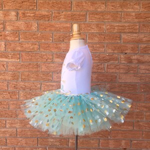 May include: A light blue tulle tutu with gold polka dots. The tutu is on a white dress form.