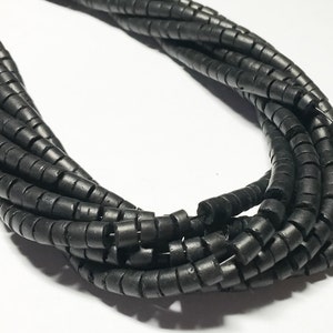 May include: A strand of black, round, and slightly coiled beads. The beads are made of a natural material and have a matte finish.