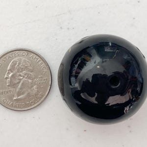 以下が含まれることがあります： 中央に小さな穴のある黒いガラスビーズ。ビーズは丸くて滑らかで、光沢のある仕上がりです。