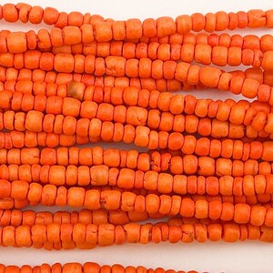 May include: A strand of orange coral beads. The beads are small and round, and they are strung together on a thin cord.