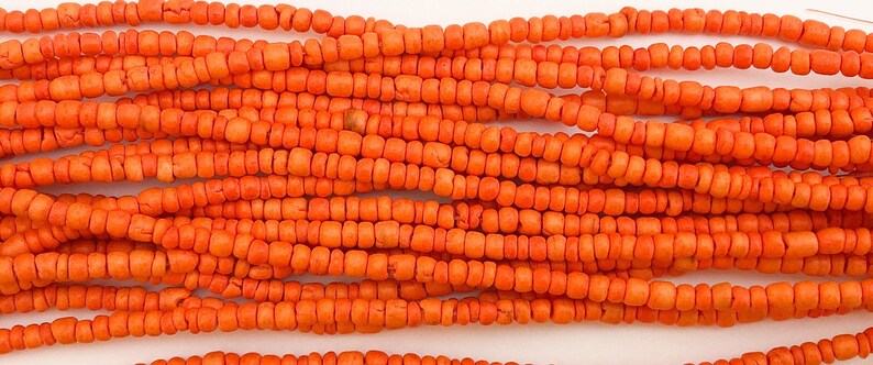 May include: A strand of orange coral beads. The beads are small and round, and they are strung together on a thin cord.