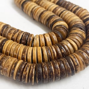May include: Close-up of several strands of natural-toned wooden beads. The beads are circular and flat, with alternating bands of light and dark brown. The beads are strung together, creating a textured and organic appearance. The image is well-lit, highlighting the natural grain of the wood.
