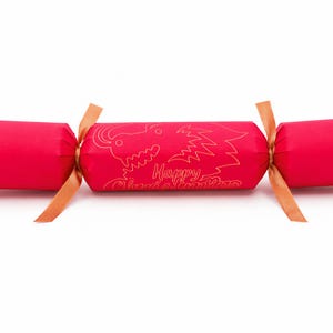A red Christmas cracker with a gold dragon design and the text "Happy Christmas" printed on it.