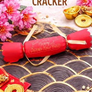 A red Chinese New Year cracker is displayed on a decorative surface, surrounded by gold coins, flowers, and other festive elements.