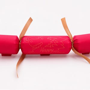 A red Christmas cracker with a gold design and the word "Happy" printed on it.