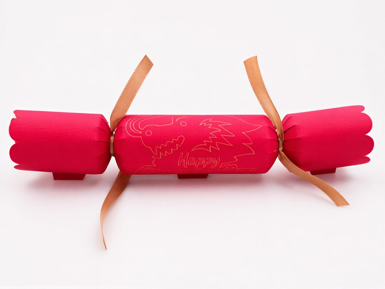 A red Christmas cracker with a gold design and the word "Happy" printed on it.