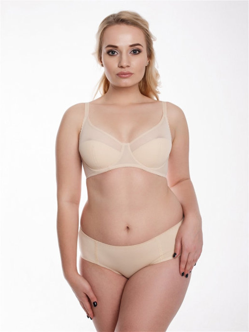 May include: A nude-colored bra and panty set. The bra has a smooth, seamless cup and adjustable straps. The panty has a high-cut leg and a smooth, seamless finish.
