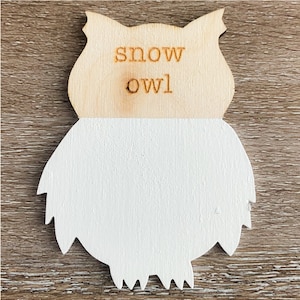 May include: Wooden cutout of a snow owl with the words "snow owl" engraved on the top. The owl is painted white.