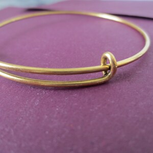 May include: A gold-toned expandable bangle bracelet with a simple design.