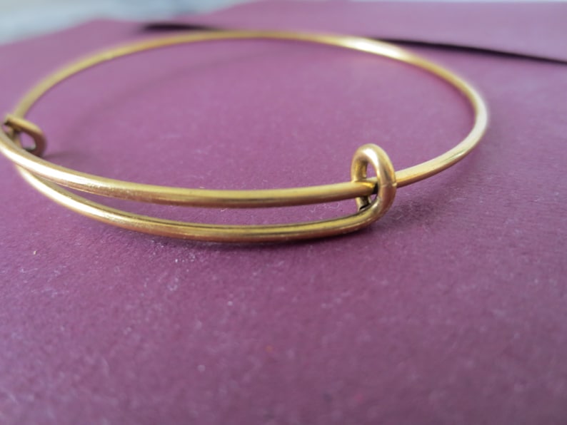 May include: A gold-toned expandable bangle bracelet with a simple design.