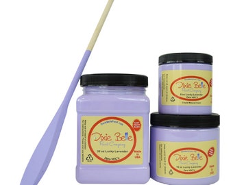 May include: Three jars of Dixie Belle paint in the color Lucky Lavender. The jars are 8 ounces, 15 ounces, and 32 ounces. The paint is a light purple color. The jars are labeled with the Dixie Belle logo and the paint color and size. The jars are on a white background.