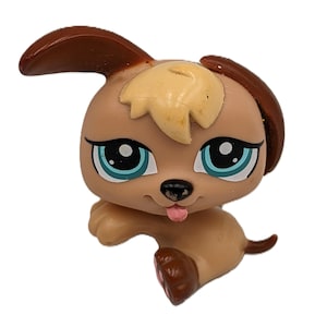 Puede incluir: Figura de cachorro marrón y marrón con grandes ojos azules y una lengua rosa que sobresale. El perro de juguete tiene orejas marrones y una cola pequeña. La figura es un juguete coleccionable.
