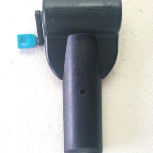 K&ouml;nnte beinhalten: Schwarzer Plastik-Handkurbel f&uuml;r ein Spielzeug. Die Kurbel hat einen kleinen blauen Plastikgriff und ein Etikett mit der Aufschrift "BATTERY 1.5V AA (LR6) X 3 MADE IN CHINA".