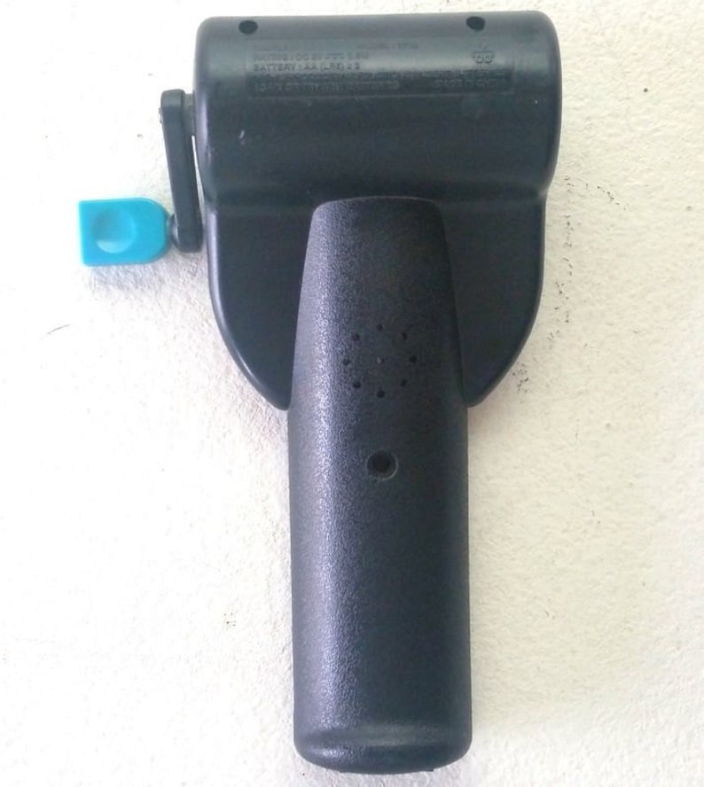 K&ouml;nnte beinhalten: Schwarzer Plastik-Handkurbel f&uuml;r ein Spielzeug. Die Kurbel hat einen kleinen blauen Plastikgriff und ein Etikett mit der Aufschrift "BATTERY 1.5V AA (LR6) X 3 MADE IN CHINA".