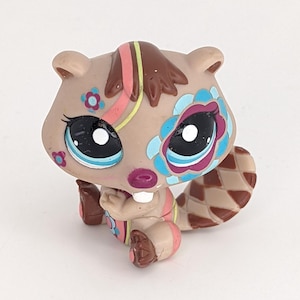 Peut inclure: Un petit castor en plastique brun avec des détails peints colorés. Le castor a des rayures roses, bleues et vertes et des fleurs peintes sur son corps. Le castor est assis sur ses haunches, les pattes devant lui.
