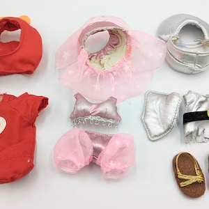 Puede incluir: Colección de ropa y accesorios para muñecas, que incluye un conjunto rojo con un corazón que dice "Devilishy Loveable", un conjunto de bailarina rosa, un conjunto de caballero plateado y sandalias marrones.