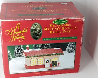 May include: A red and white box with a picture of a house on the front. The box is for a Christmas village house that is a tribute to the movie "It's a Wonderful Life". The text on the box reads "A Wonderful Holiday, New For 1996, Mr. and Mrs. Martini's House in Bailey Park, A Tribute To The Movie It's A Wonderful Life."