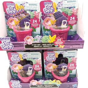 Puede incluir: Cuatro sets de juguetes Littlest Pet Shop en exhibición. Cada set presenta una maceta rosa con un pequeño juguete en su interior, rodeada de un embalaje colorido con temática floral y de mariposas. El embalaje incluye el número 24 y una advertencia sobre piezas pequeñas.