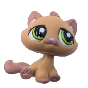 Puede incluir: Una pequeña figura de gato de color tostado con grandes ojos verdes, nariz rosa y detalles rosas en las orejas y patas. El gato tiene un cuerpo de plástico moldeado liso con diseño de cabeza oscilante, cola curva y almohadillas detalladas.