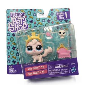 Puede incluir: Un set de juguetes Littlest Pet Shop en su empaque original que incluye una figura de gato blanco con grandes ojos azules y una corona amarilla. Incluye una pequeña silla rosa con un detalle de corona dorada, una cabeza de gato blanca y un cepillo.