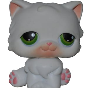 Puede incluir: Una figura de gato blanco con grandes ojos verdes y detalles rosas en las orejas, la nariz y las patas. El gato de juguete tiene una apariencia esponjosa y una expresión sonriente, con un pequeño mechón de pelo en la cabeza.