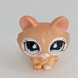 Peut inclure: Figurine de chat beige et crème avec de grands yeux bleus et un motif d'étoile blanche. Le chat a des oreilles bordées de rose et une petite poitrine crème. La figurine est un jouet de collection.