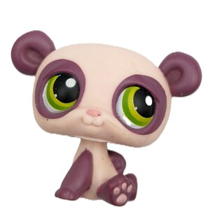 May include: A small, panda-like figurine with a light pink head and dark purple ears, paws, and accents around the eyes. The figurine has large, expressive eyes with green and black irises. The panda is in a sitting position.