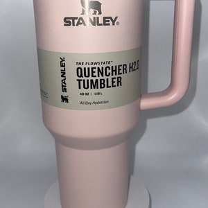May include: A pink Stanley Quencher H2.0 Tumbler with a stainless steel lid and handle. The tumbler is 40 ounces or 1.18 liters and says "All Day Hydration".