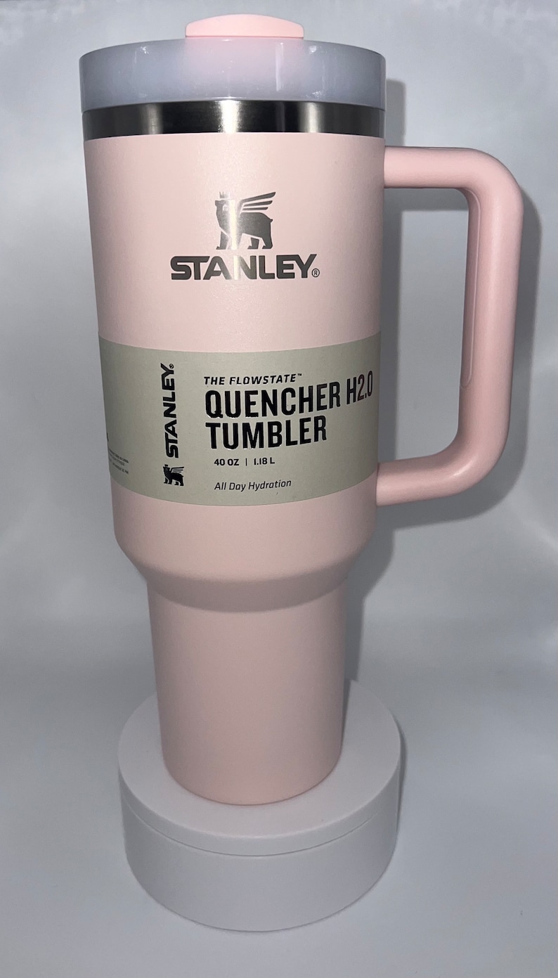 May include: A pink Stanley Quencher H2.0 Tumbler with a stainless steel lid and handle. The tumbler is 40 ounces or 1.18 liters and says "All Day Hydration".