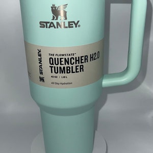 May include: A light blue stainless steel Stanley Quencher H2.0 Tumbler with a black label that reads "The Flowstate" Quencher H2.0 Tumbler, 40 oz | 1.18 L, All Day Hydration".