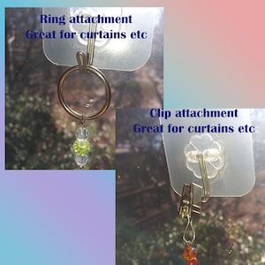 Two window curtain clips, one with a ring attachment and the other with a clip attachment. Both clips are silver and have clear plastic stick on hooks. The ring attachment has a string of green and clear beads hanging from it. The clip attachment has a string of orange and clear beads hanging from it. The text on the image reads 'Ring attachment Great for curtains etc' and 'Clip attachment Great for curtains etc'.