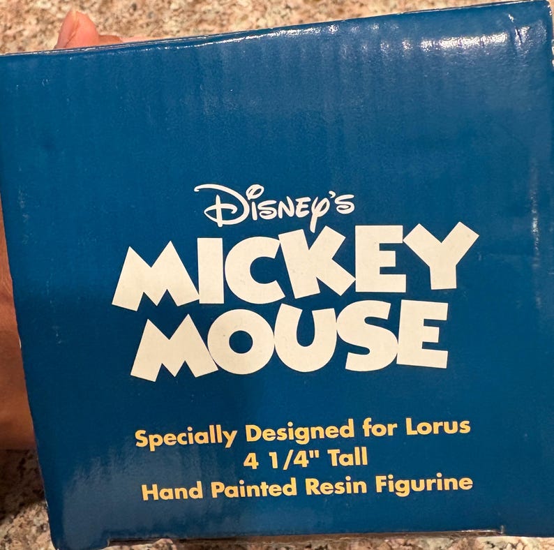 May include: A blue box with the Disney's Mickey Mouse logo in white. The text reads "Specially Designed for Lorus, 4 1/4" Tall, Hand Painted Resin Figurine."