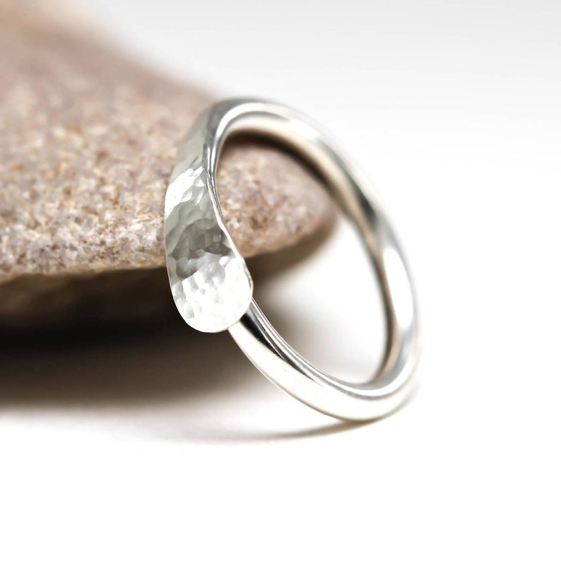 May include: A silver hammered ring with a rounded, hammered band.