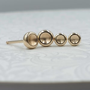 May include: Gold stud earrings featuring four graduated round discs. The discs are smooth and have a slightly concave shape.