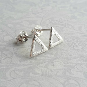 May include: A pair of silver triangle stud earrings with a textured hammered finish.