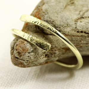 May include: A gold ring with a hammered finish, twisted into a double band.