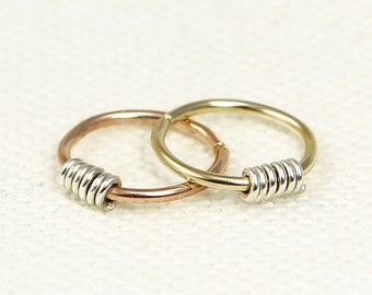 May include: Two hoop earrings, one gold and one rose gold, with a silver coil accent on each.