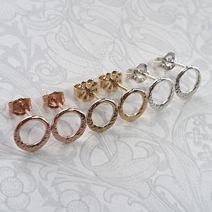 May include: Three pairs of small, hammered, hoop earrings in gold, rose gold, and silver.